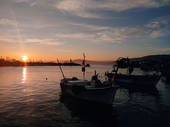 Boats moored in sea against sky during sunset