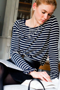 Young woman reading book while sitting on bench