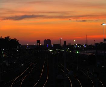 View of illuminated city against cloudy sky during sunset