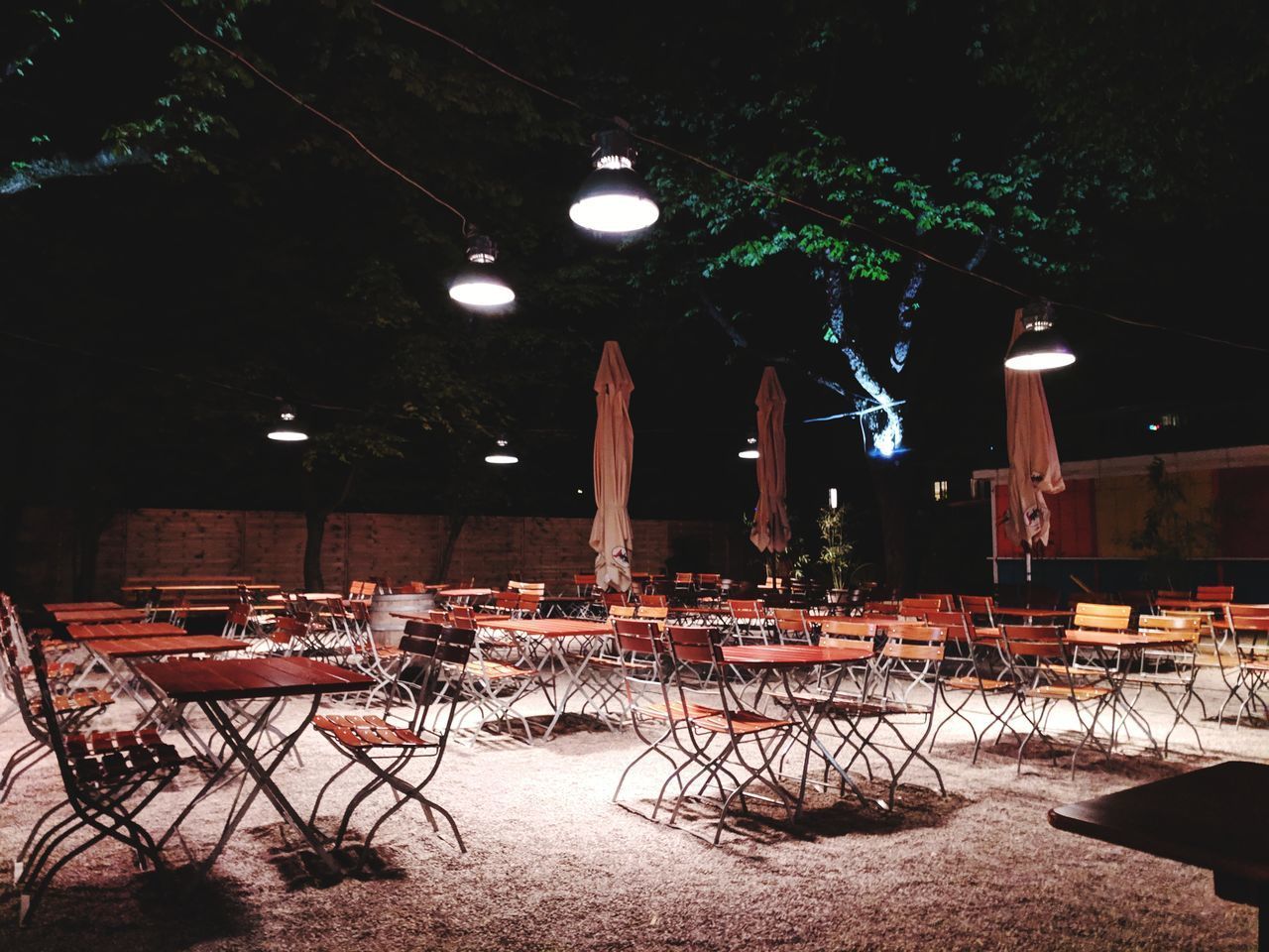 CHAIRS AND TABLES AT ILLUMINATED RESTAURANT