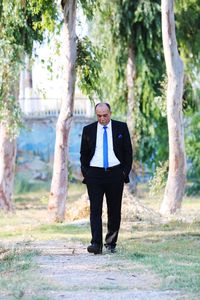 Full length of man standing by tree trunk