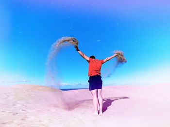 Full length of woman standing on beach against blue sky