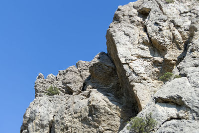 Low angle view of rock formation against clear blue sky