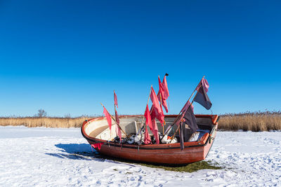 Ship on snowy field against clear blue sky
