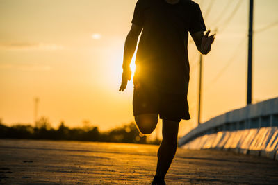 Rear view of silhouette man walking against sky during sunset