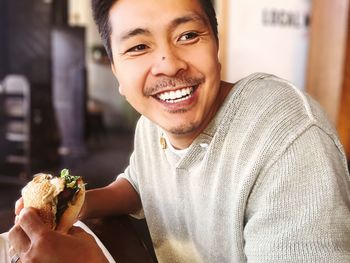 Portrait of happy man eating food at home