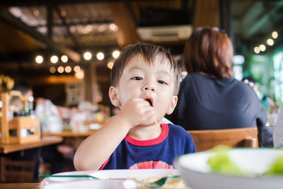 Cute baby boy having meal at restaurant