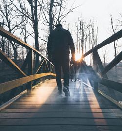 Rear view of man walking on bridge