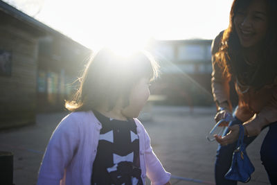 Happy mother playing with daughter on footpath during sunny day