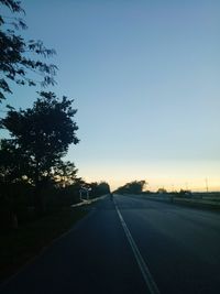 Road amidst trees against clear sky