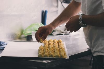 Cropped image of man preparing dumplings at kitchen counter