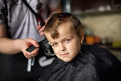Portrait of cute boy sitting at barber shop