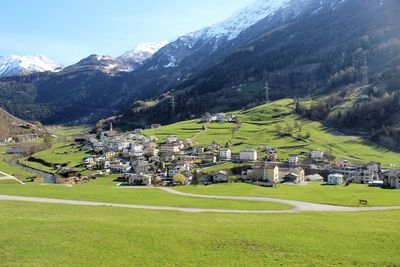 Houses on field by mountain against sky