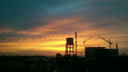 Silhouette cranes at construction site
