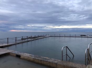 Pier over sea against sky during sunset