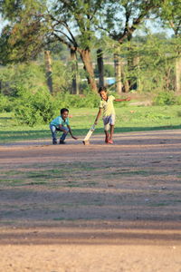 Boys playing cricket on land