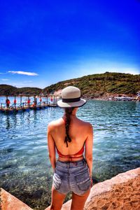 Rear view of woman standing at harbor against sky