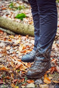 Low section of person standing on autumn leaves after mud