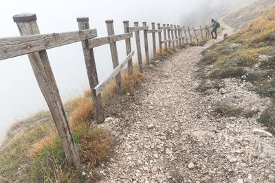 Hiker standing by wooden fence at monti simbruini in foggy weather