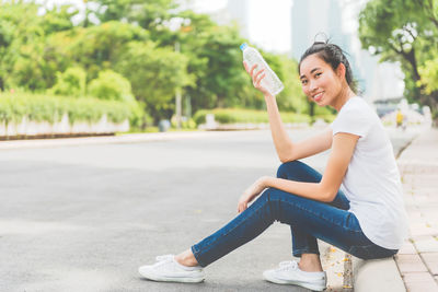 Portrait of smiling woman sitting on road in city
