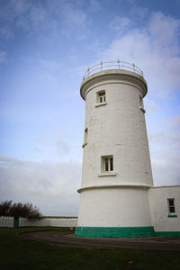 Lighthouse by sea against sky