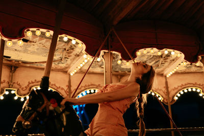 Millennial woman riding carousel horse