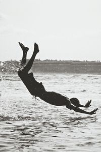 Young woman jumping on sea against sky
