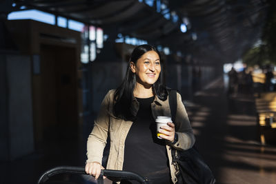 View of woman holding disposable cup at train station