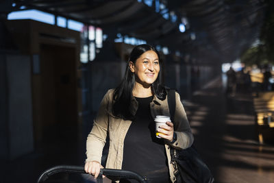 View of woman holding disposable cup at train station