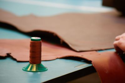 Close-up of spool and leather on table in workshop