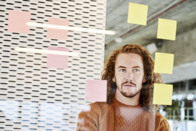 Man looking at adhesive notes stick on glass material at home