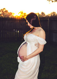 Midsection of woman standing against sky during sunset