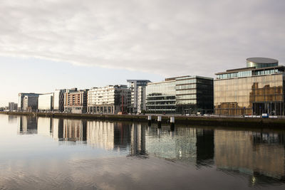 Buildings in dublin by river liffey against sky in city