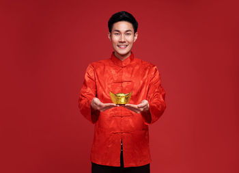 Portrait of a smiling young man against red background