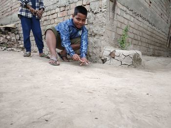 Full length of man sitting against wall