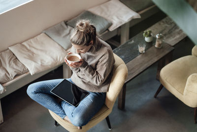 High angle view of woman sitting on sofa at home