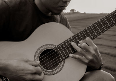 Midsection of man playing guitar outdoors