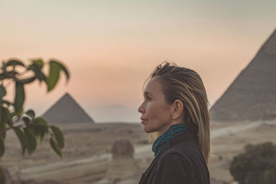 Woman looking away against pyramids and sky