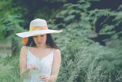 Woman wearing hat while standing by plants