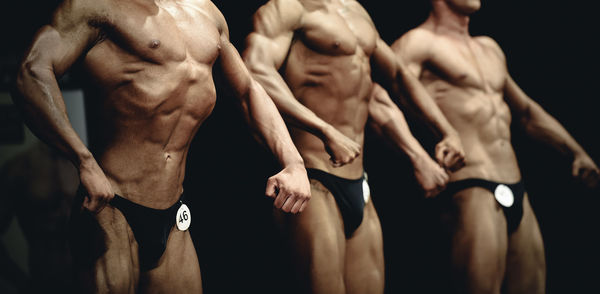 Body builders flexing muscles while posing on stage