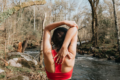 Rear view of woman stretching at forest