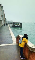 Rear view of people on boat in sea against clear sky