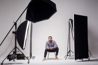 Full length portrait of young man photographing against white background