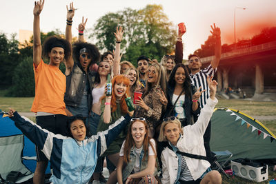 Portrait of happy friends standing in front of people