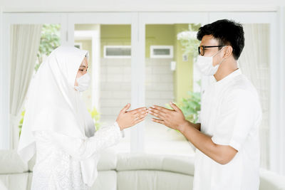 Side view of a young man with woman standing at home