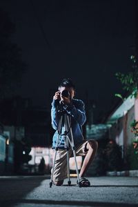 Woman with umbrella standing on road at night