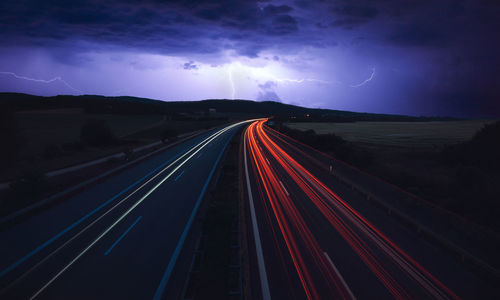 Light trails on highway against sky at night