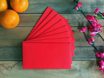 Red envelopes and fruits by flowers on table