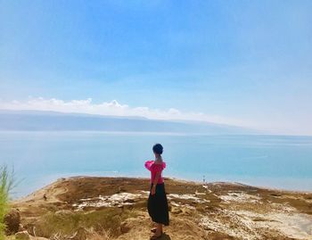 Rear view of young woman standing at beach