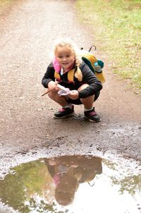 Smiling girl crouching by puddle